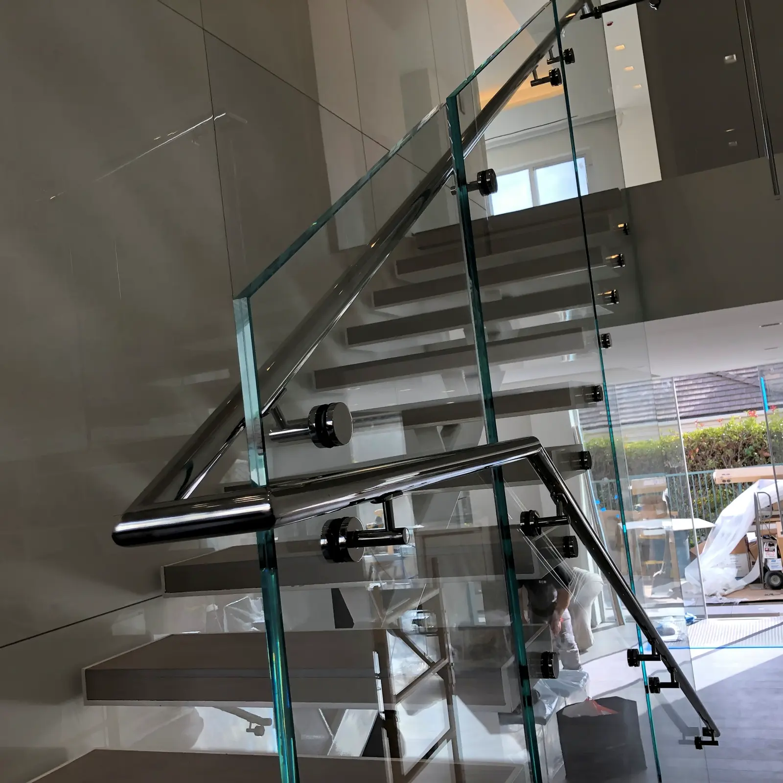 Finished glass stair railing with aligned standoffs and a floating white stair