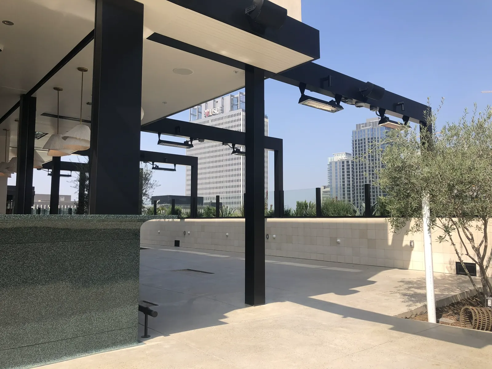 Outdoor patio under a black metal structure with glass partitions