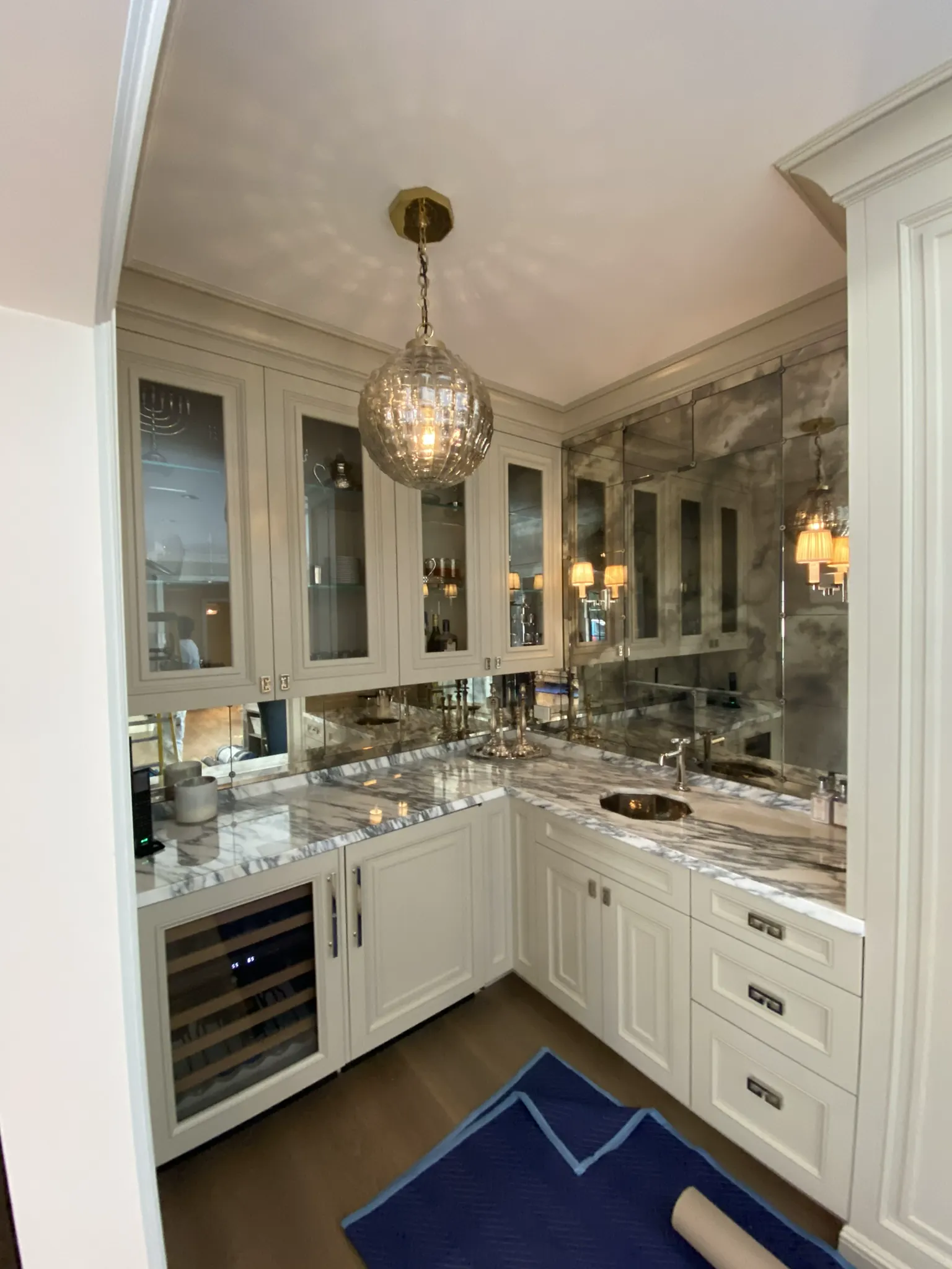 Antiqued mirror wall behind a marble wet bar