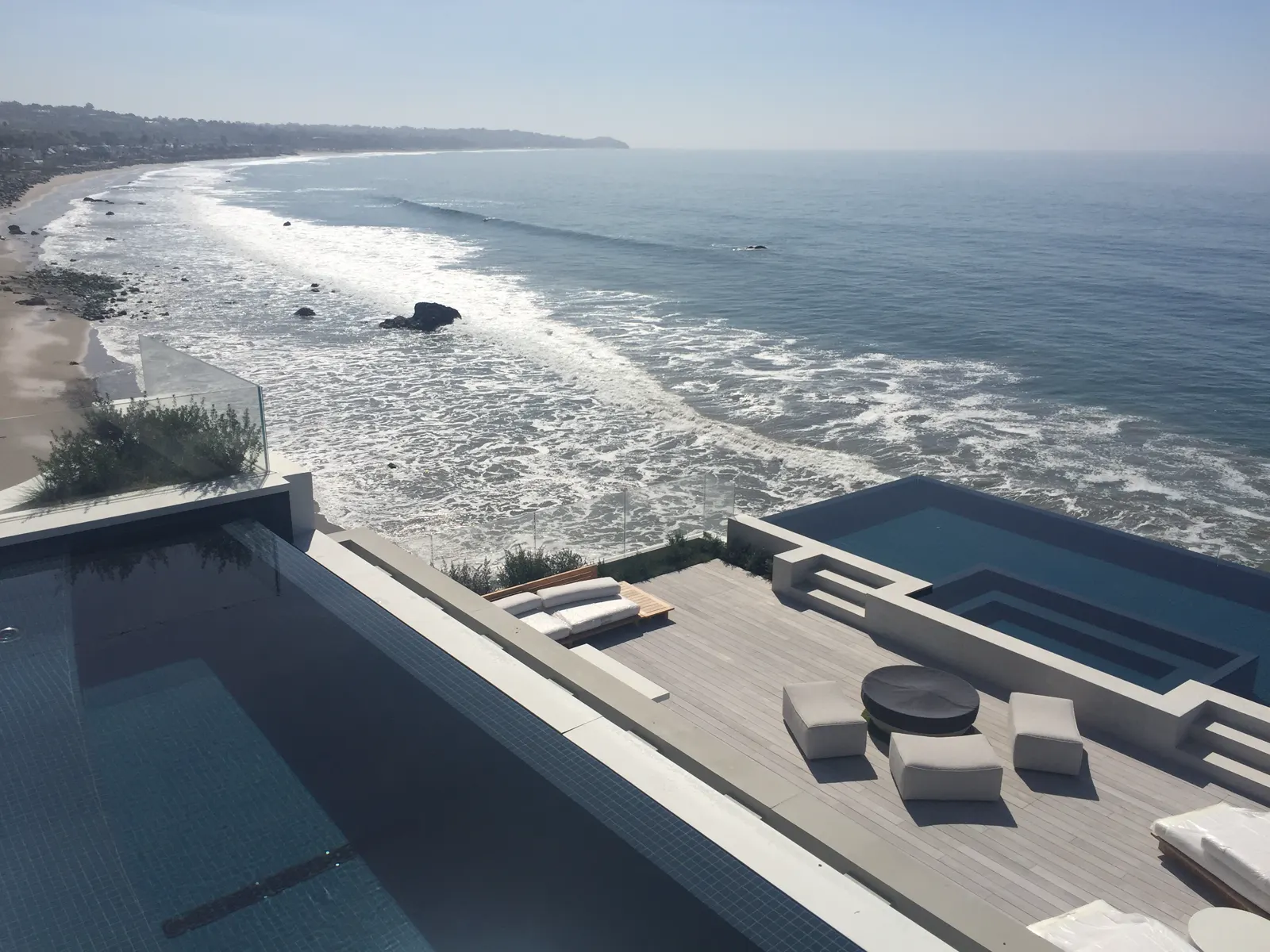 Frameless glass terrace railing at a coastal residence with reflecting pool