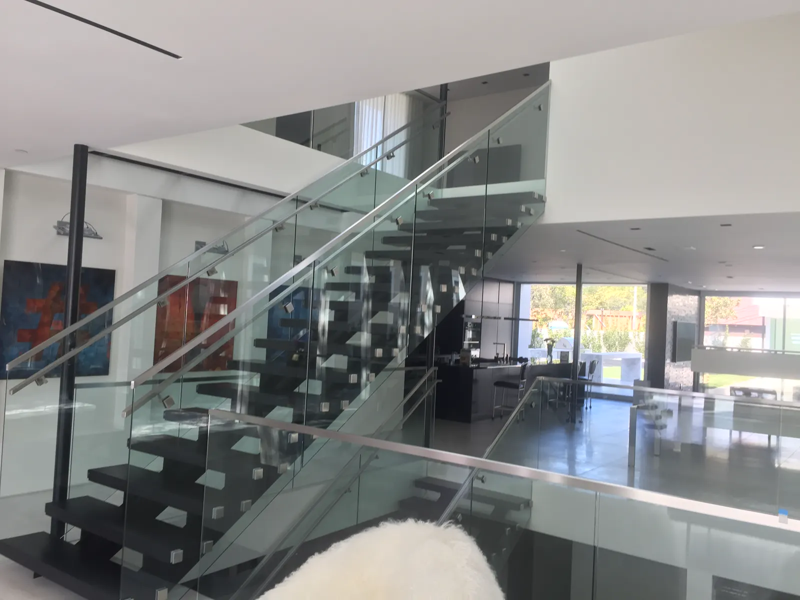Interior glass stair railing with stainless standoffs in a multilevel home
