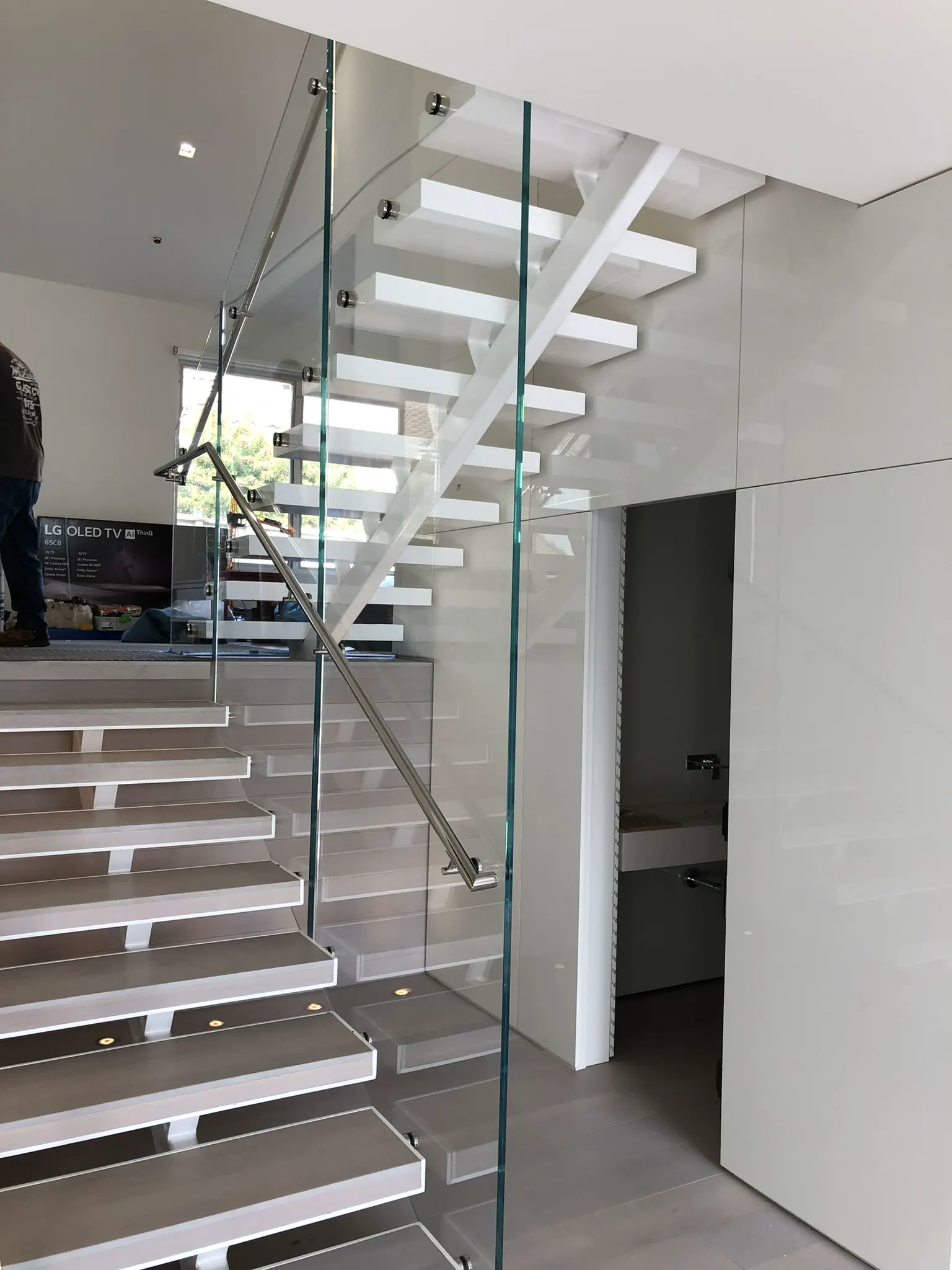 White interior staircase with side-mounted glass railings
