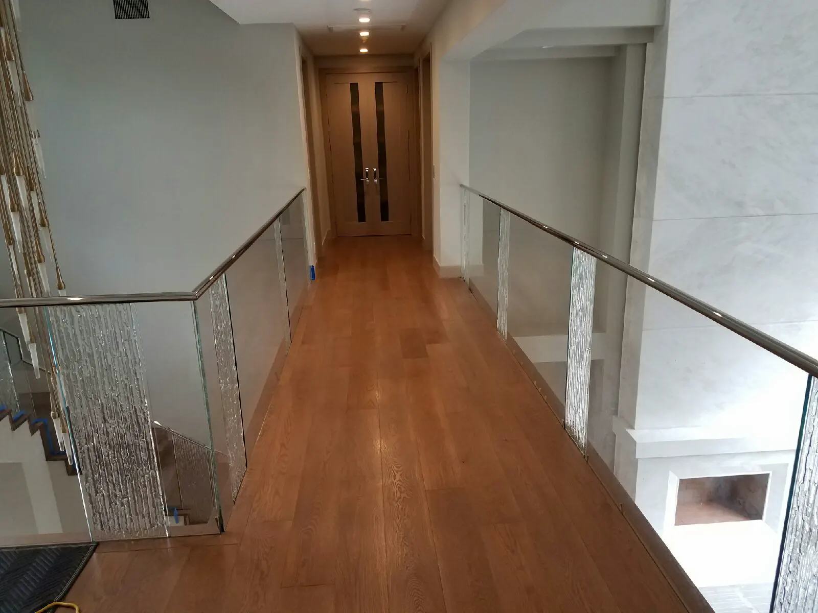 Long glass railing along an interior hallway overlooking the floor below