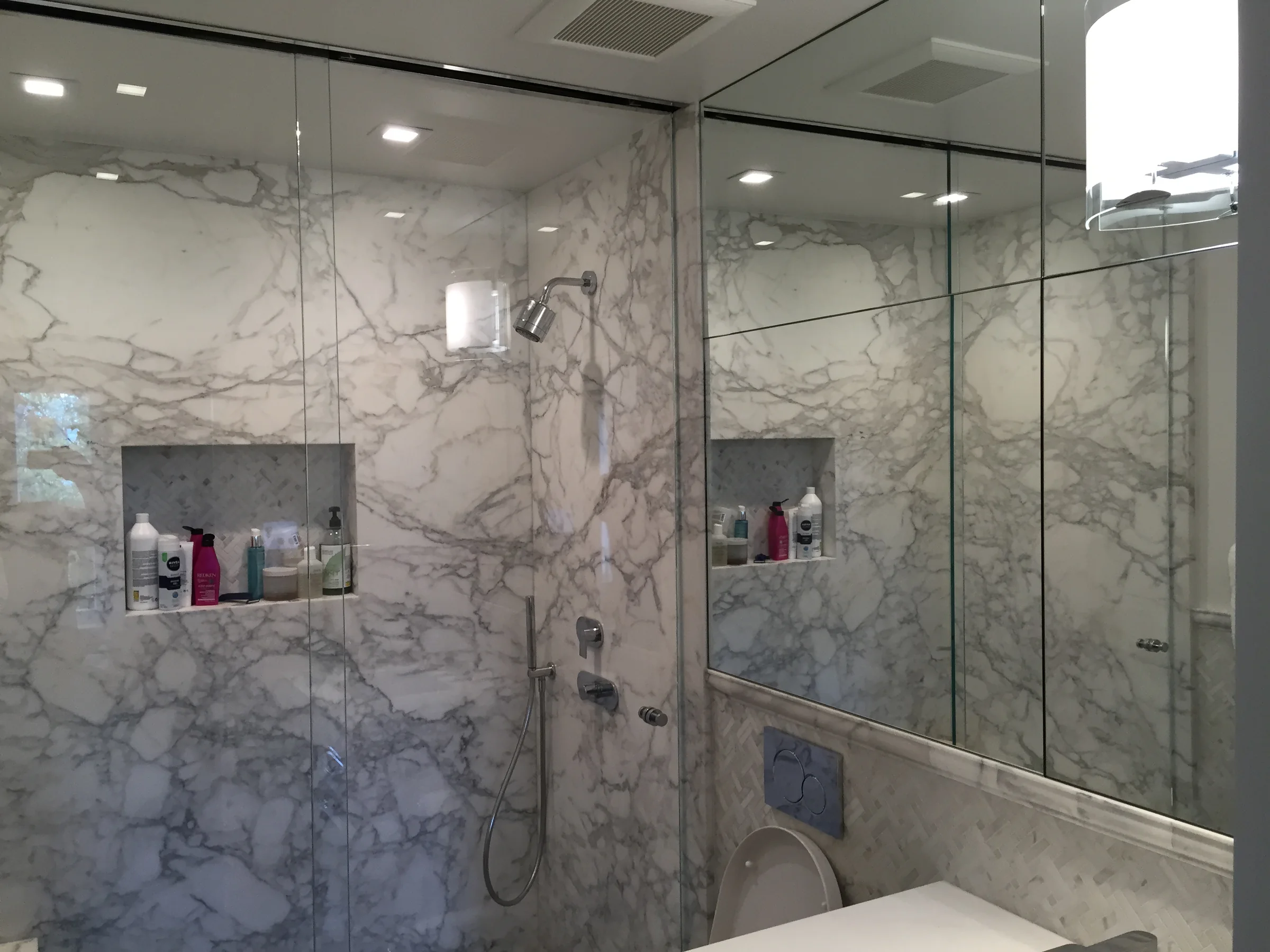 Frameless glass shower enclosure in a marble bathroom
