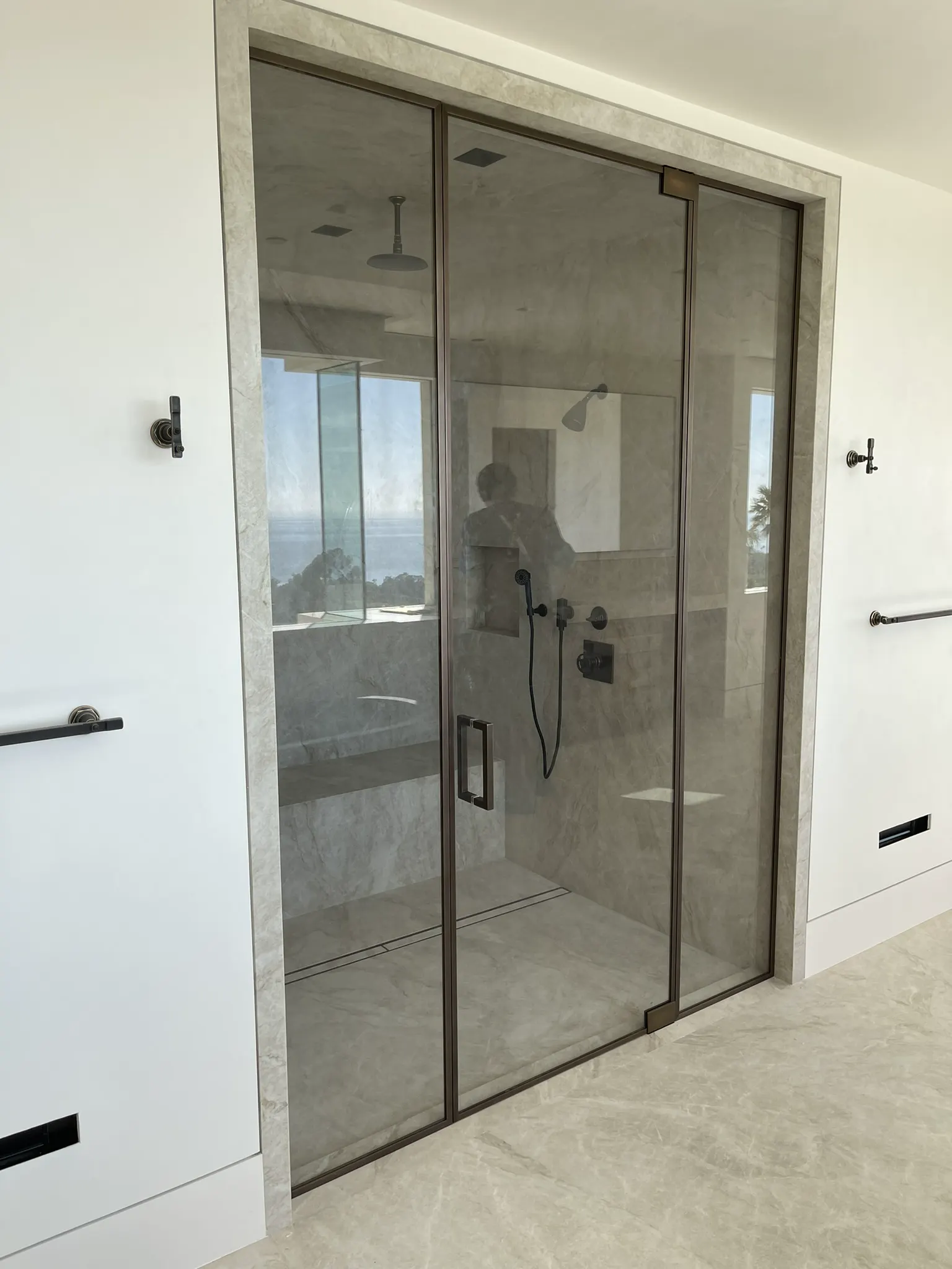 Frameless shower door with thin black hardware in a white-tiled bath