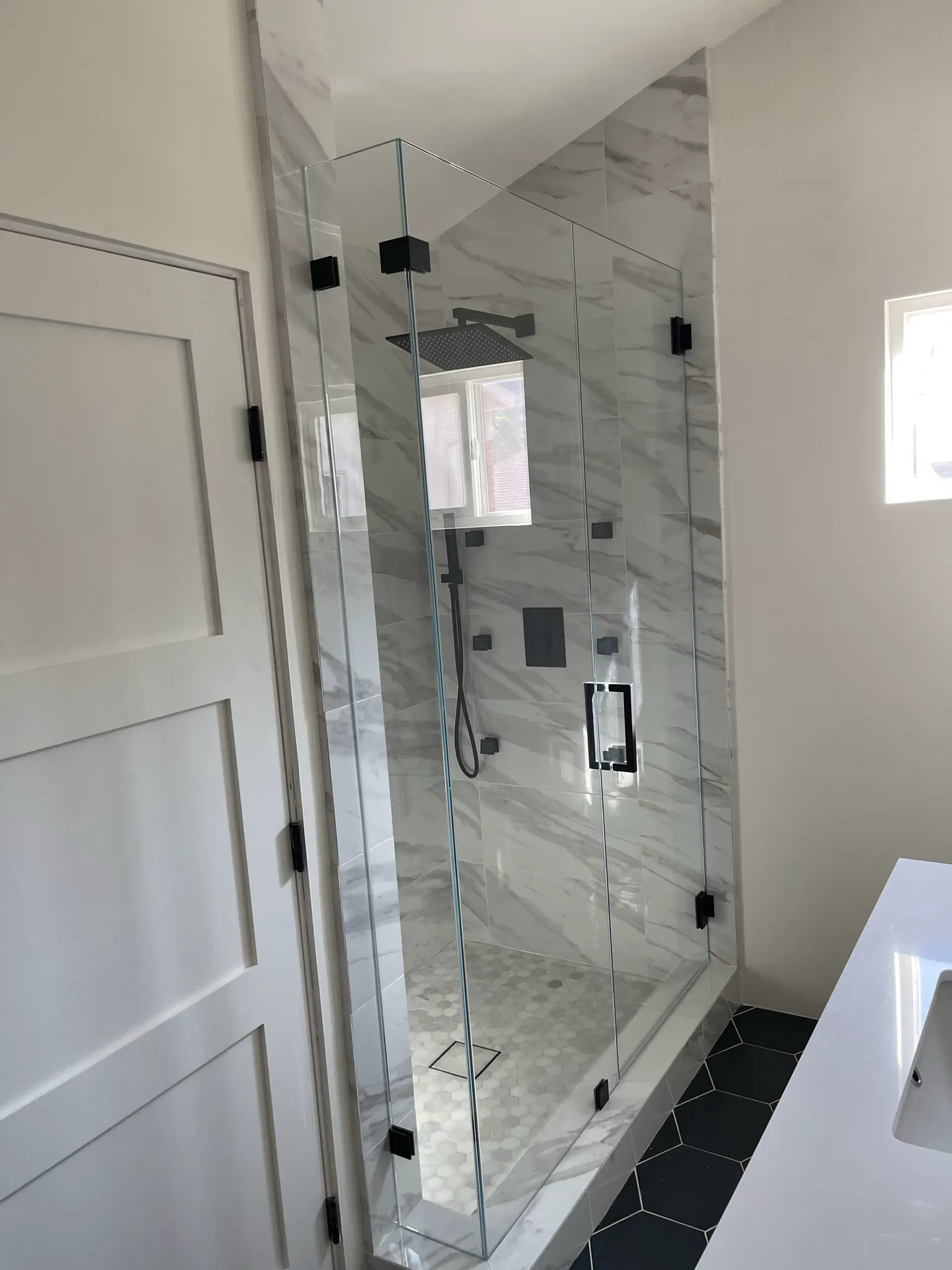 Frameless marble shower with matte black hinges and handle