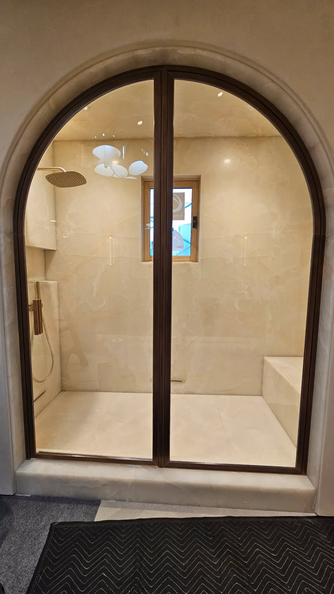 Arched glass shower door in a dark metal frame