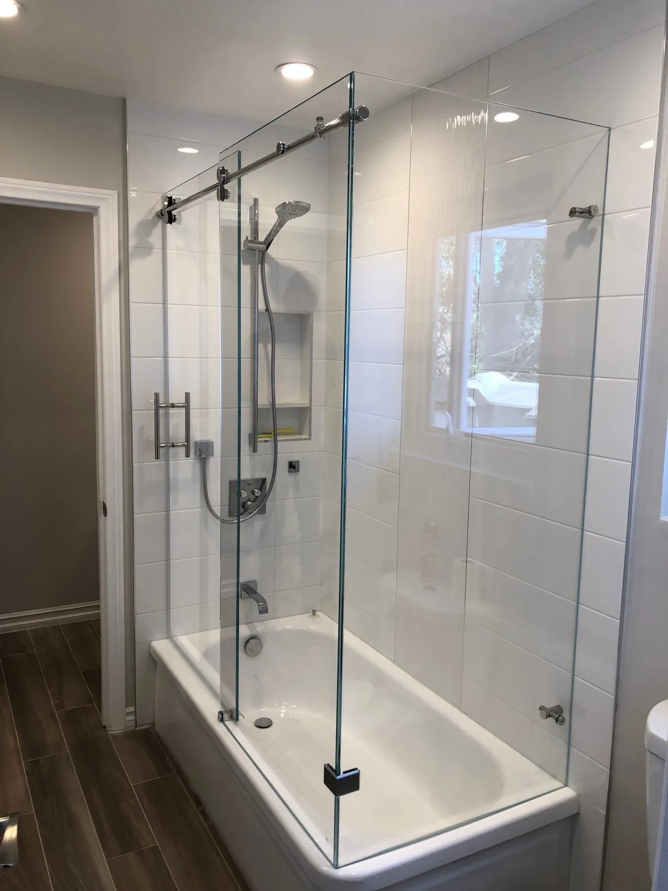 Frameless sliding glass shower door over a bathtub