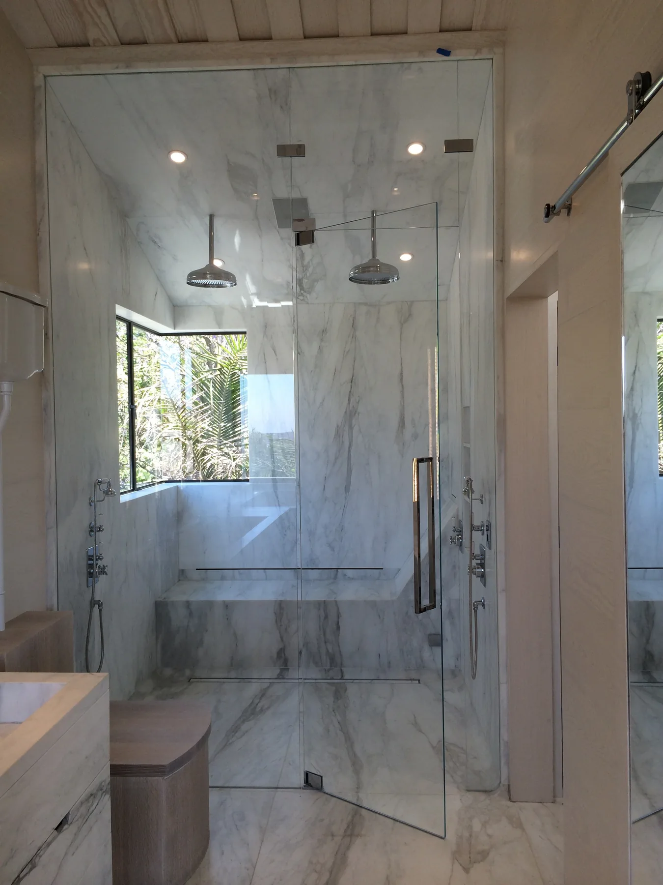Floor-to-ceiling frameless glass shower in a marble bathroom