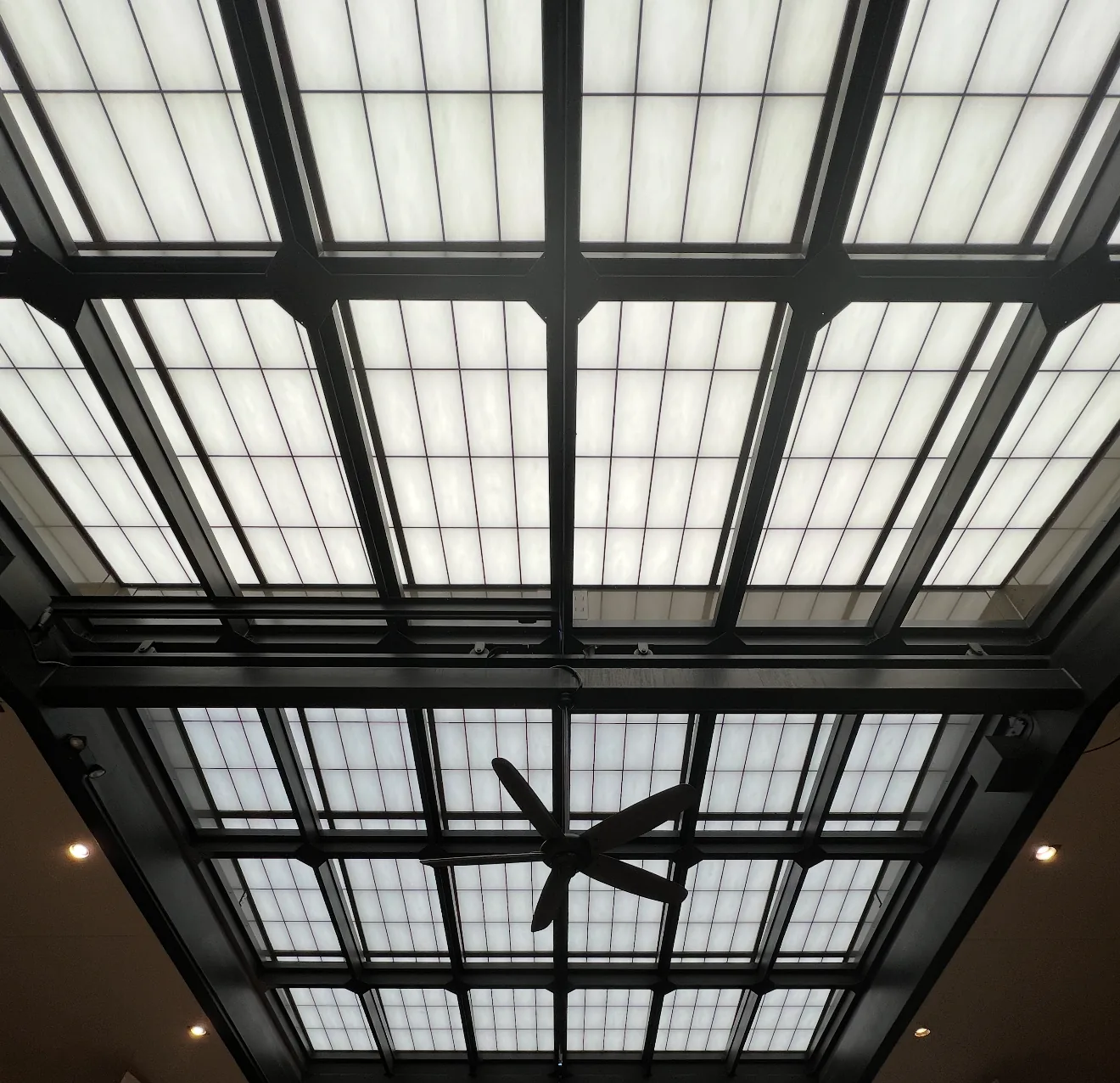 Looking up at a frosted glass skylight in a dark metal grid
