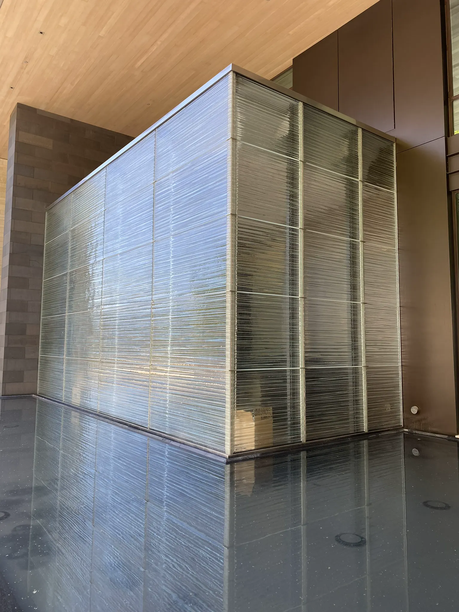 Ribbed textured glass structure beside a dark reflecting pool