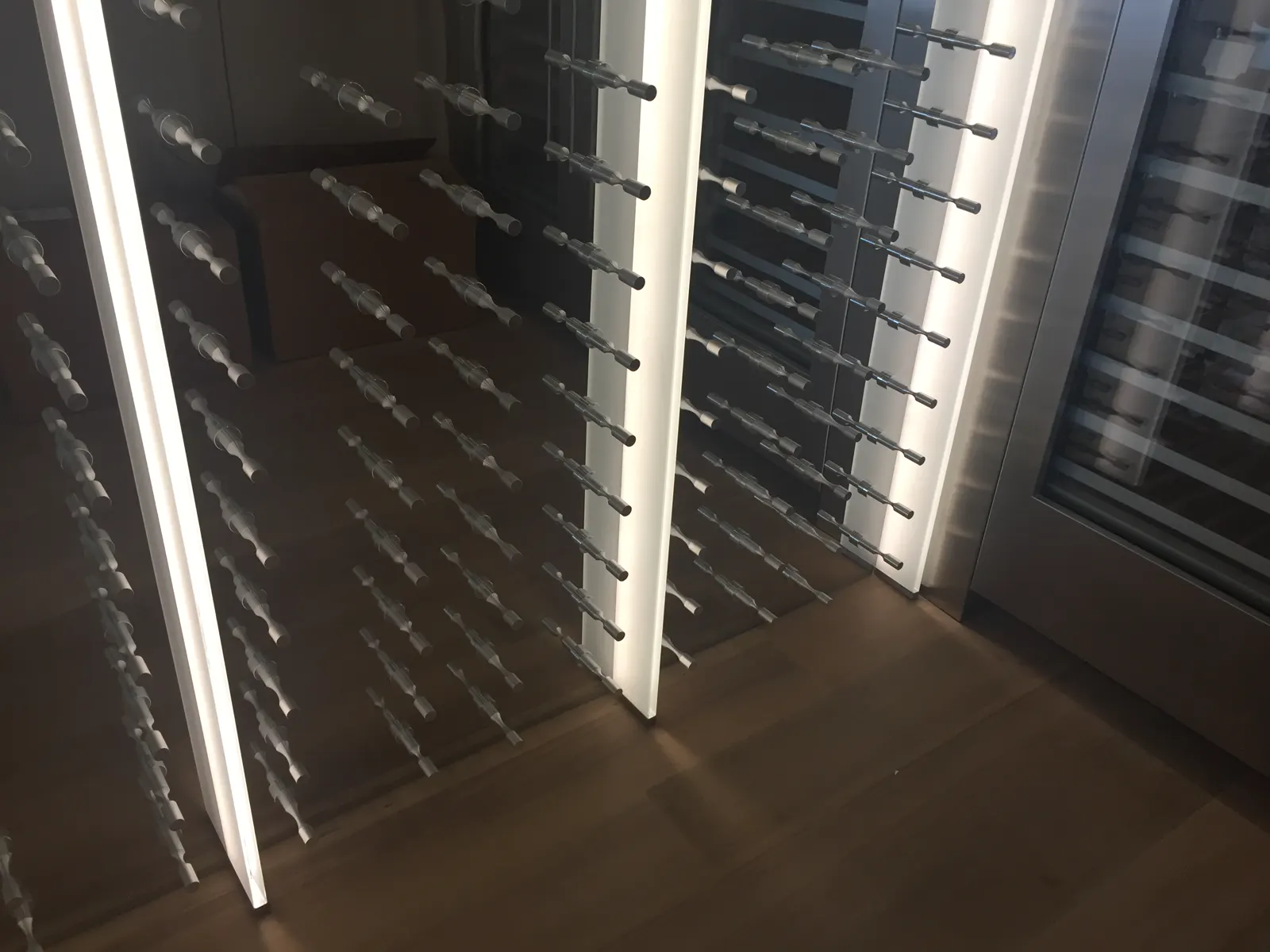 Glass wine room with horizontal metal bottle pegs