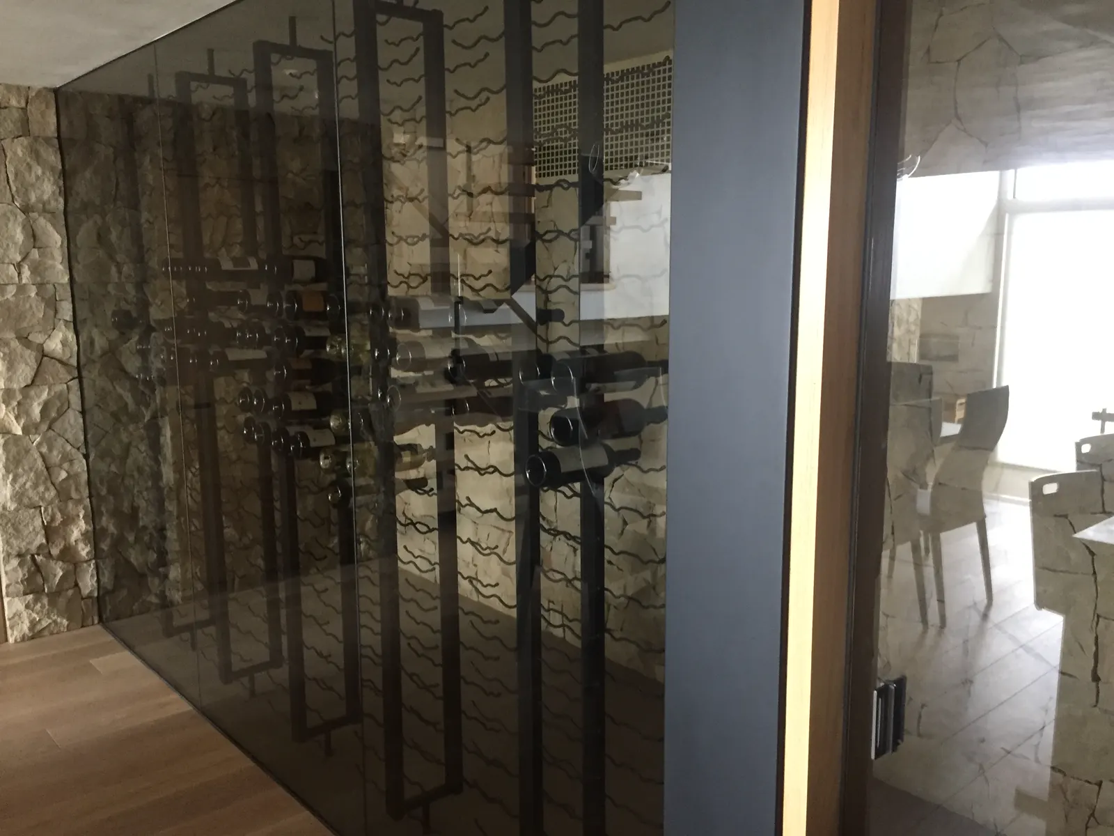 Wine room enclosed in dark-framed glass walls